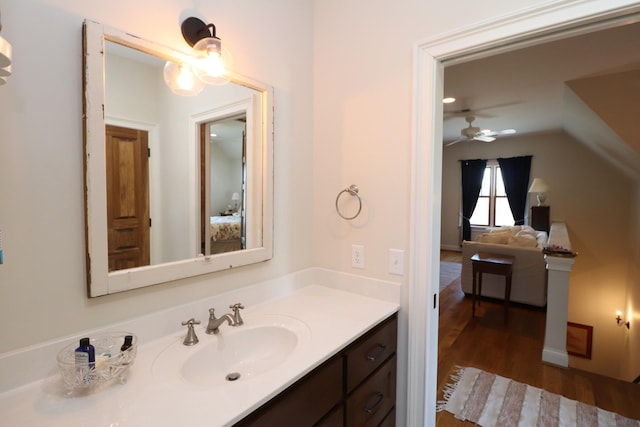 ensuite bathroom with a ceiling fan, ensuite bathroom, wood finished floors, vanity, and vaulted ceiling