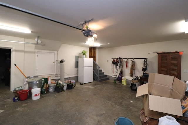 garage featuring electric panel, a garage door opener, and freestanding refrigerator