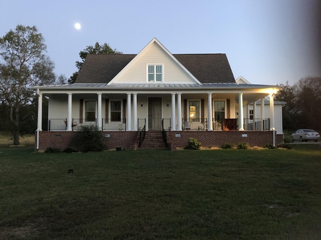 farmhouse-style home featuring a standing seam roof, a front yard, and covered porch