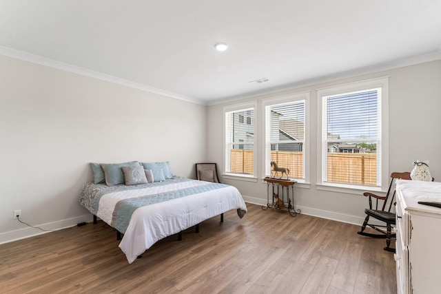 bedroom featuring light wood-type flooring, visible vents, crown molding, and baseboards