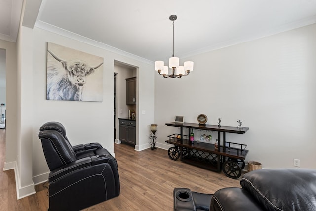 living room featuring ornamental molding, a chandelier, baseboards, and wood finished floors