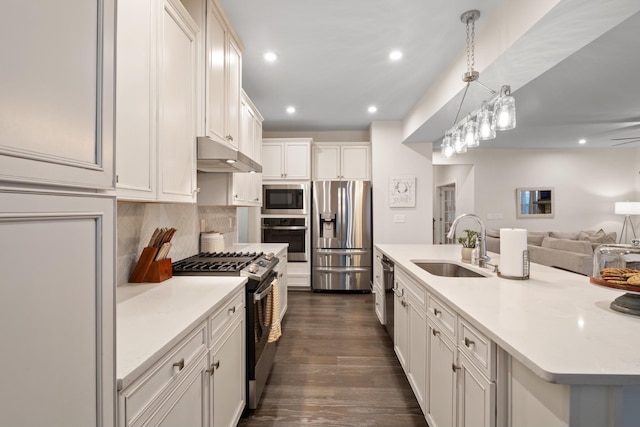 kitchen featuring appliances with stainless steel finishes, light countertops, under cabinet range hood, a sink, and recessed lighting