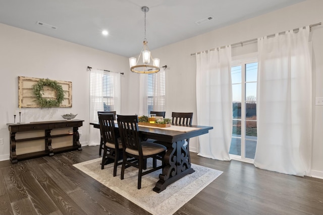 dining space with dark wood-style floors, visible vents, and an inviting chandelier