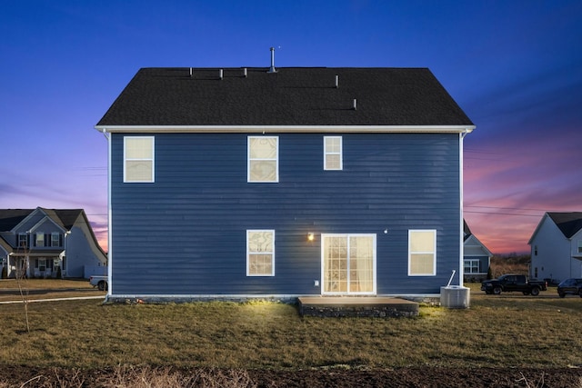 back of property at dusk with a patio, central AC unit, and a lawn