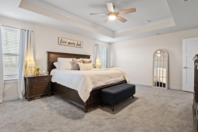 bedroom with a raised ceiling, light carpet, and baseboards