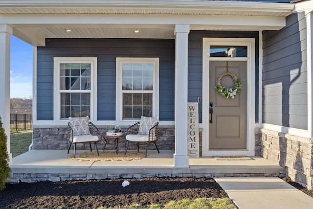 doorway to property featuring covered porch and stone siding