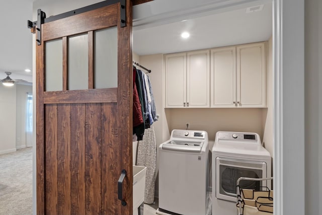 washroom with light colored carpet, cabinet space, a barn door, independent washer and dryer, and baseboards