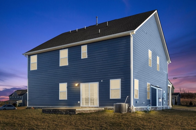 back of property with central AC unit and a lawn