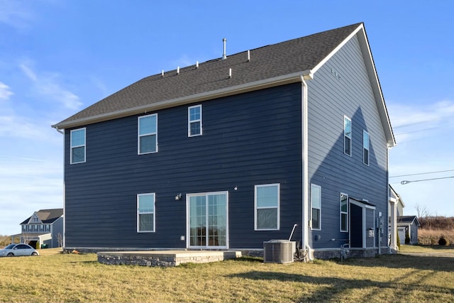 back of house with central AC unit, a lawn, a patio area, and a shingled roof