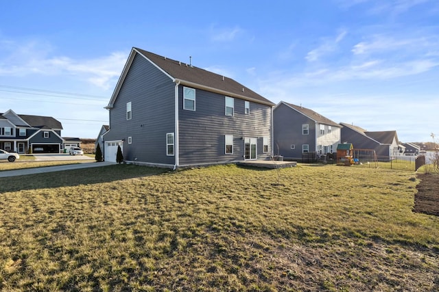 back of house featuring an attached garage, fence, a yard, concrete driveway, and a residential view