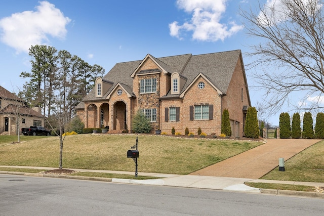 view of front of home with brick siding, a shingled roof, and a front yard