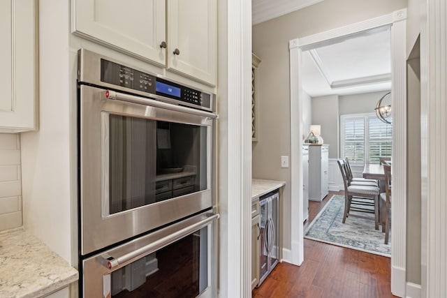 kitchen featuring dark wood-style floors, light stone counters, wine cooler, a notable chandelier, and stainless steel double oven