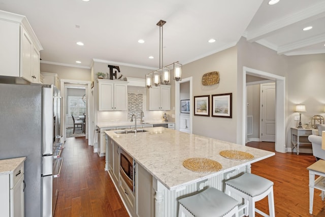 kitchen with stainless steel appliances, dark wood-style flooring, a sink, and a large island with sink