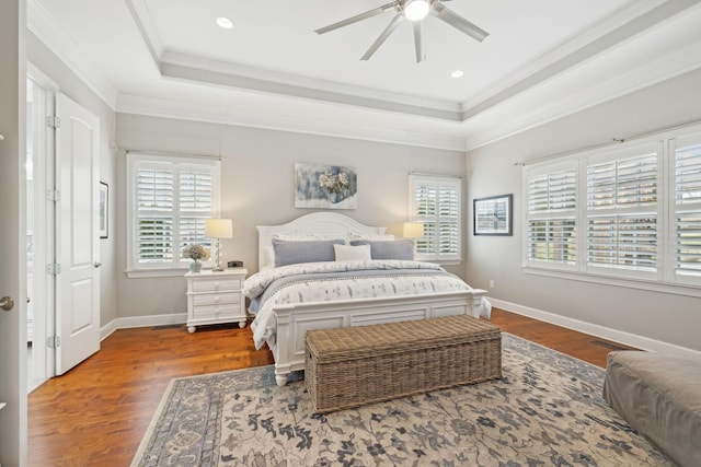 bedroom with crown molding, baseboards, a raised ceiling, and wood finished floors