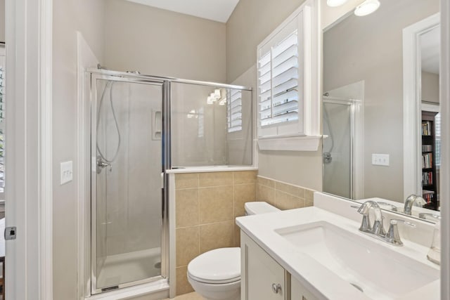 full bathroom featuring toilet, a stall shower, tile walls, and vanity