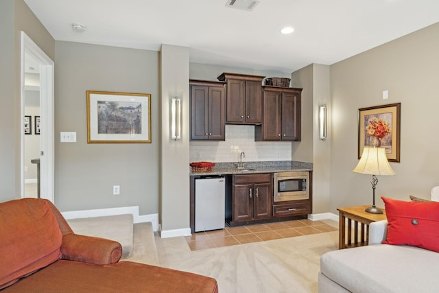 bar with light tile patterned floors, refrigerator, a sink, decorative backsplash, and stainless steel microwave