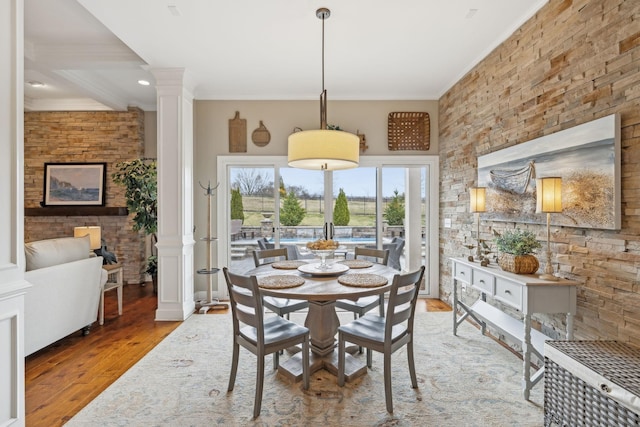 dining space with ornamental molding, wood finished floors, and ornate columns