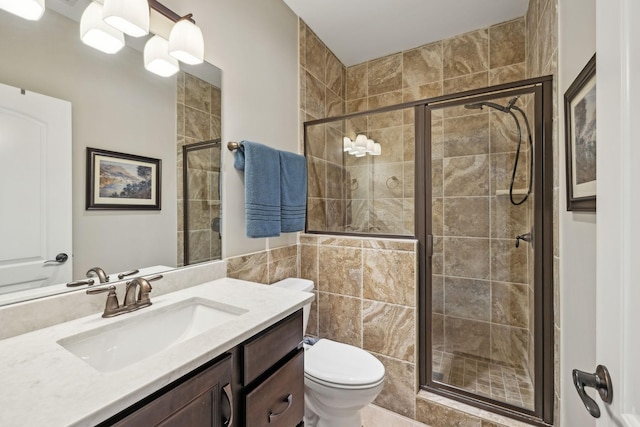 bathroom with toilet, a stall shower, and vanity