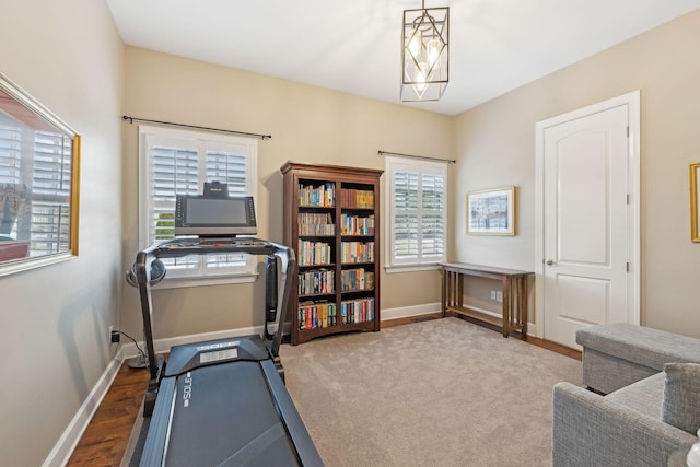 exercise room with a notable chandelier, baseboards, and wood finished floors