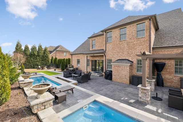 rear view of property featuring brick siding, roof with shingles, an outdoor pool, and a patio