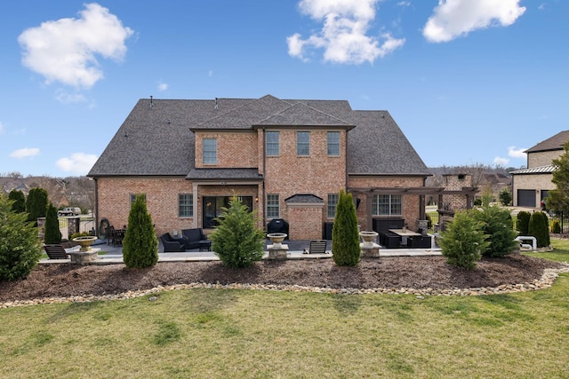 rear view of property with a patio, a yard, roof with shingles, and brick siding