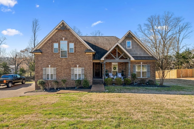 view of front of house with brick siding, a front lawn, and fence