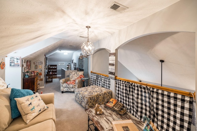 living area featuring a textured ceiling, a notable chandelier, carpet flooring, visible vents, and vaulted ceiling