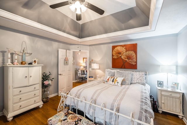 bedroom with dark wood-type flooring, a tray ceiling, and a ceiling fan