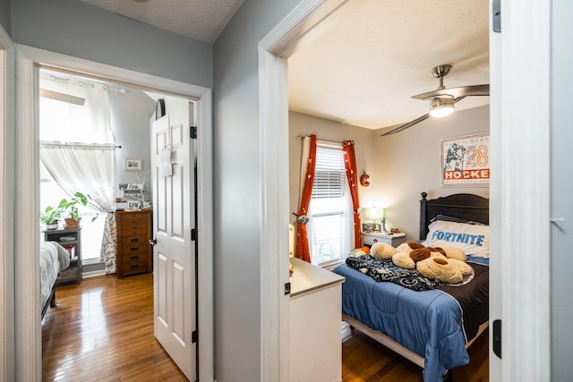 bedroom with a textured ceiling, ceiling fan, and hardwood / wood-style floors