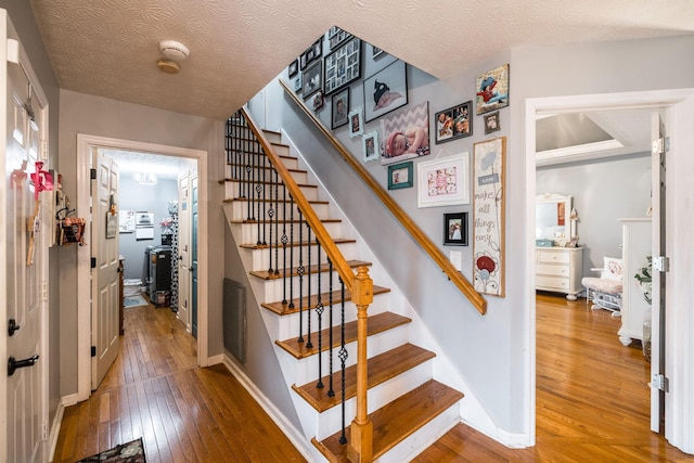 stairs with hardwood / wood-style flooring, baseboards, and a textured ceiling