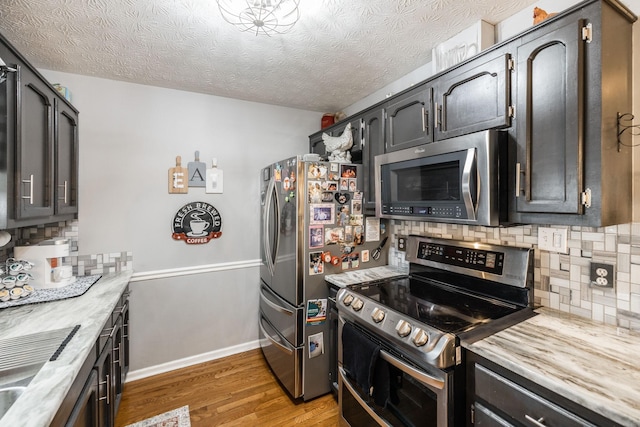 kitchen featuring baseboards, light wood-style flooring, stainless steel appliances, a textured ceiling, and light countertops