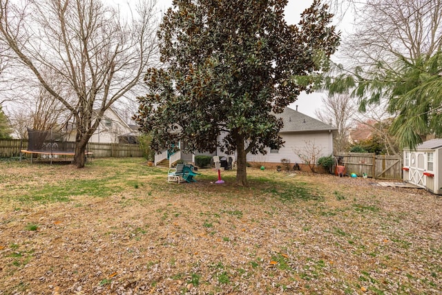 view of yard with a trampoline, an outbuilding, a fenced backyard, and entry steps