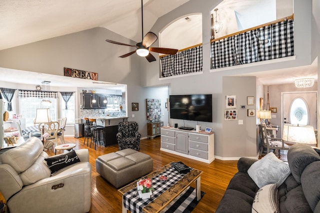 living area with high vaulted ceiling, wood finished floors, a ceiling fan, and baseboards