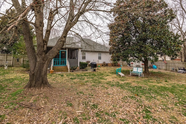 back of property with a sunroom, a fenced backyard, a shingled roof, and a yard