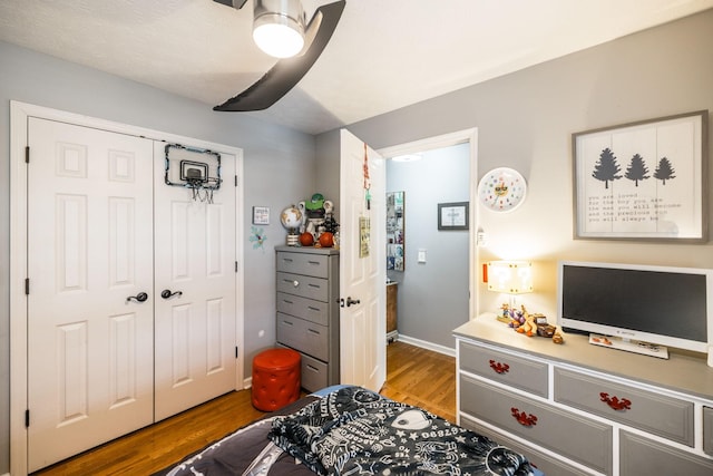 bedroom with baseboards, a closet, a ceiling fan, and wood finished floors