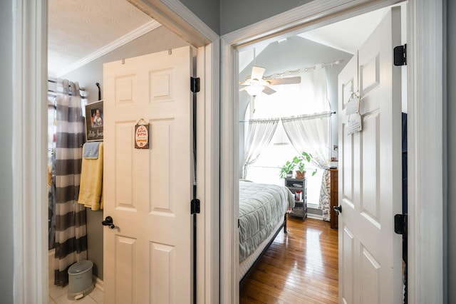 interior space with vaulted ceiling, wood-type flooring, crown molding, and a textured ceiling