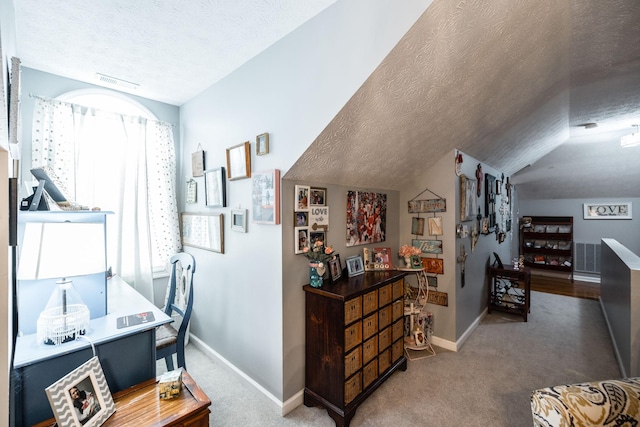 corridor featuring lofted ceiling, carpet, a textured ceiling, and baseboards