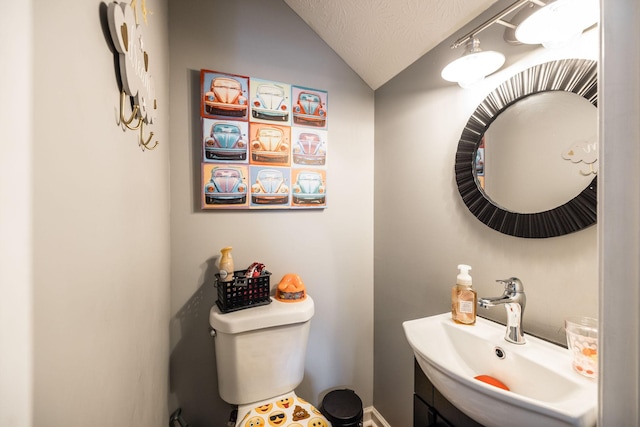 bathroom with lofted ceiling, toilet, a textured ceiling, and vanity