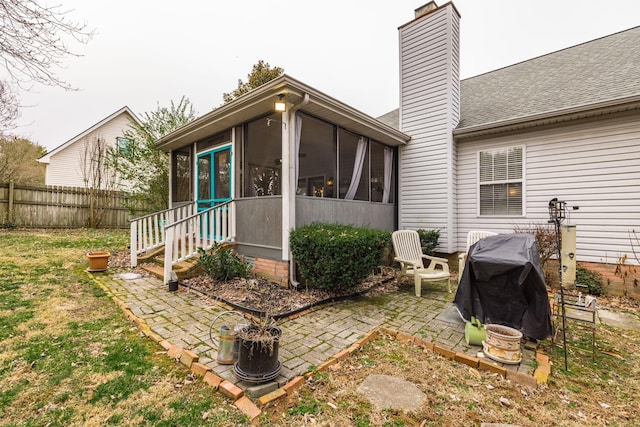 rear view of property with a patio, a chimney, a shingled roof, a sunroom, and fence