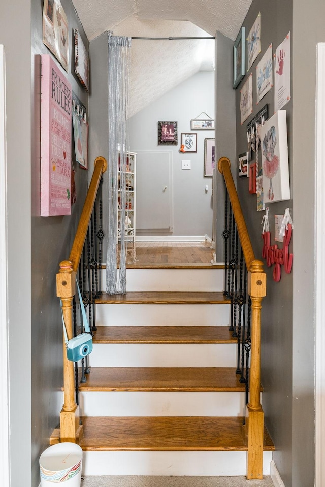 stairs featuring vaulted ceiling and a textured ceiling