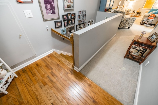 corridor featuring hardwood / wood-style flooring, an upstairs landing, and baseboards