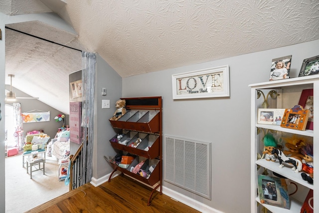 interior space featuring lofted ceiling, visible vents, a textured ceiling, and wood finished floors