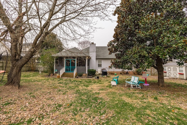 rear view of house featuring a yard, a chimney, fence, and a sunroom