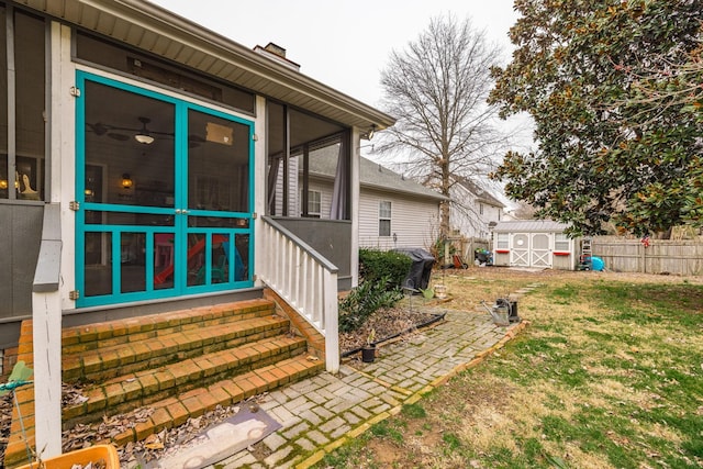 view of yard with an outbuilding, a sunroom, fence, and a storage shed