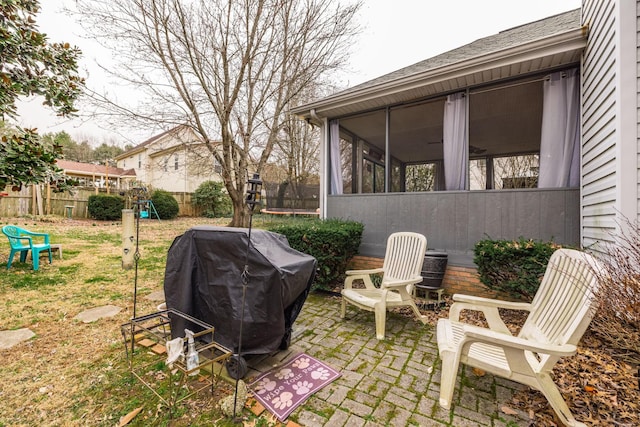 view of patio / terrace featuring a trampoline, fence, a sunroom, and a grill