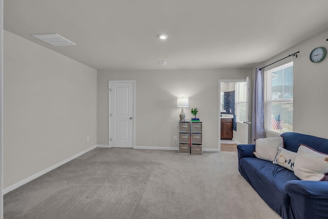 living area with light colored carpet, visible vents, and baseboards