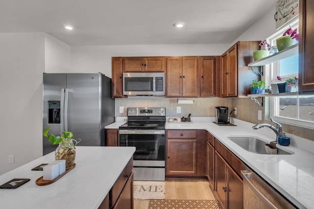 kitchen with open shelves, light wood-style flooring, backsplash, appliances with stainless steel finishes, and a sink