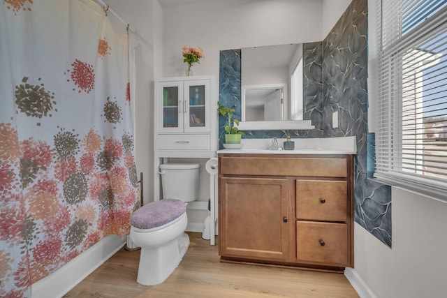 bathroom with baseboards, a shower with shower curtain, toilet, wood finished floors, and vanity