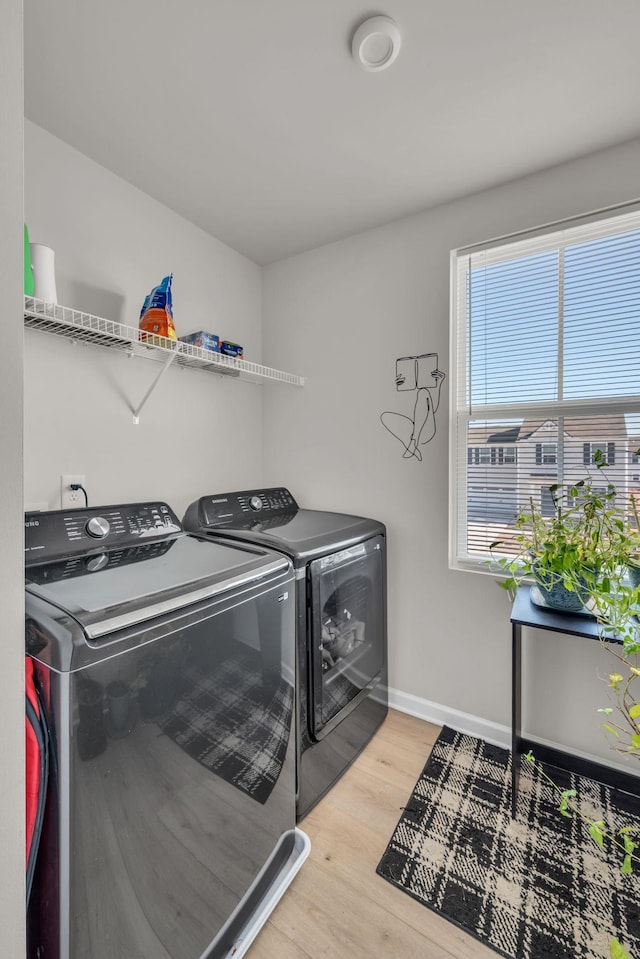 laundry area featuring baseboards, laundry area, washing machine and dryer, and light wood-style floors