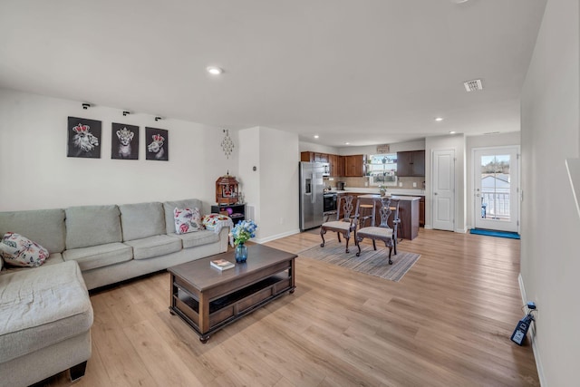 living room featuring light wood-style floors, recessed lighting, visible vents, and baseboards